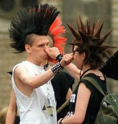 two people with mohawks on their heads and one is holding something in his mouth