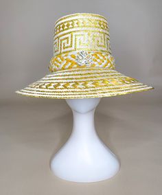 Product Description Handcrafted by Wayuu artisans The “Caña Flecha”, which is a plant native to the region, is skillfully woven to create a wide-brimmed hat that provides protection from the sun and rain. Has incorporated our signature Monstera leaf and a pin style of our name tag, both gold-platted This hat features a distinctive design that combines form and function. They are decorated with elaborate details, such as colorful ribbons and woven patterns, that reflect the rich cultural heritage Gold Bohemian Brimmed Hat, Natural Toquilla Straw Hat With High Crown, Yellow Bohemian Fedora Straw Hat, Gold Wide Brim Straw Hat, Handmade Gold Wide Brim Hat, Traditional Wide Brim Panama Hat In Toquilla Straw, Traditional Wide Brim Panama Hat, Traditional Handwoven Panama Hat In Toquilla Straw, Traditional Handwoven Toquilla Straw Panama Hat