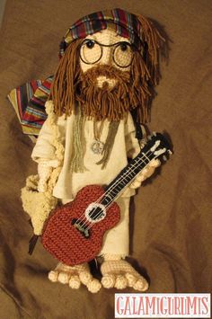 a crocheted stuffed animal with a beard and glasses holding a red ukulee