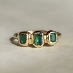 Three emeralds are embedded into this magical piece of treasure! Bezel set in 14k gold, this ring is inspired by ancient jewelry. Currently size 5.5 Due to the nature of the settings, this ring can only be resized up or down 1 size, if you need a size that is outside of the 1 size range, email me! Depending on my stock, I can make you a custom ring in any size! The inclusions and imperfections on these stones are natural. I choose to use perfectly imperfect stones because of the personality they bring to the piece. One of a kind Each emerald is different..making this a one of a kind piece. I don't mass produce jewelry, I handcraft each one out of wax first then cast them in 14k gold. This ensures every one of a kind ring is truly unique and special in their own way. Heirloom Style Three Stone Green Emerald Ring, Heirloom Green Emerald Ring With Three Stones, Emerald Ring With Bezel Setting For May Birthstone, Heirloom Green Emerald Jewelry, Green Emerald Three Stone Ring In 14k Gold, Timeless Green Emerald Ring In 14k Gold, Timeless Green Emerald Ring Stamped 14k, Timeless 14k Gold Emerald Cut Ring, Heirloom Emerald Jewelry With Bezel Setting