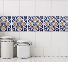 a blue and white tiled wall with two canisters next to it