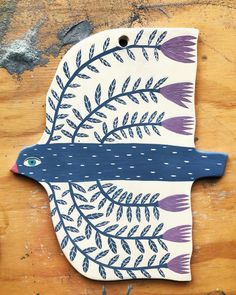 a ceramic bird with purple feathers and leaves on it