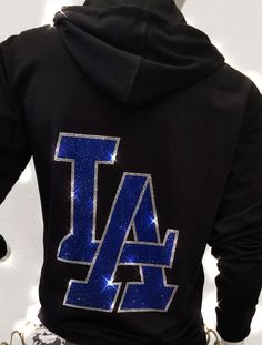 Super sparkle LA rhinestone hoodie. This stunning hoodie has a large sapphire rhinestone LA logo on the back. Front has smaller silver LA logo on the left side, and a bling string!! We use high quality, multi-cut rhinestones for all our designs. This makes them super sparkly and really cool. Perfect to wear to a Dodger game, to the beach or anytime! Great gift for any fan of the Dodgers or LA! Nice weight black fleece hoodie is a unisex fit. Please check the measurements below, you maybe able to Cheer Moves, Diamond Hoodie, Rhinestone Hoodie, Dodger Game, Causual Outfits, Black Fleece, Black Rhinestone, Fan Gear, Small Chest