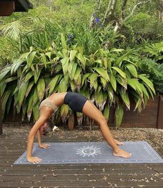 a woman is doing yoga in front of some plants