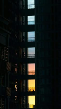 the sun is setting in between two tall buildings with balconies on each floor