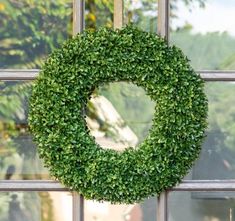 a green wreath hanging on the side of a window