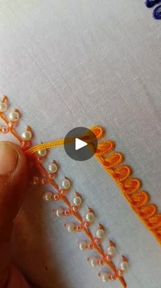 someone is stitching something on the fabric with their fingernails and using an orange thread