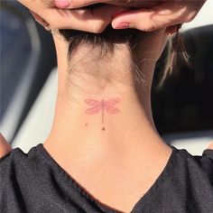 the back of a woman's neck with a small dragonfly tattoo on it