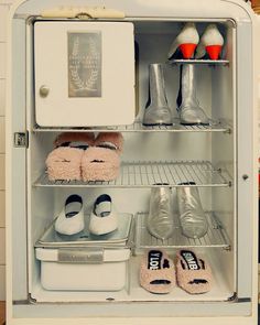 an open refrigerator with shoes and other items in it