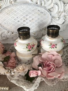 two white vases with pink flowers on a lace doily