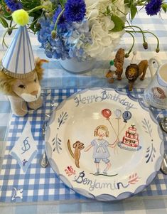 a blue and white checkered table cloth with a birthday plate on it, two stuffed animals next to the plate