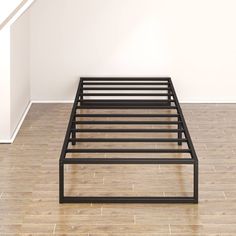 a metal bed frame sitting on top of a hard wood floor next to a white wall