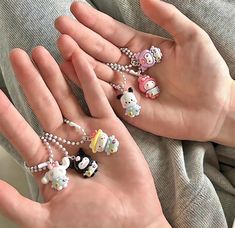 a person's hand holding several small rings with hello kitty charms attached to them