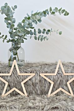 two wooden stars sitting on top of a rug next to a vase filled with flowers