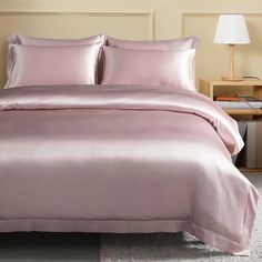 a bed with a pink comforter and two pillows on top of it in a bedroom