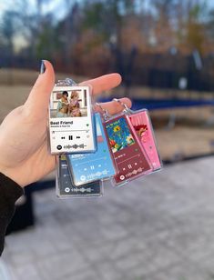 a person holding up three different colored cell phones in their hand, one with an mp3 player attached to it