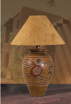 a lamp that is sitting on a table next to a vase with a bird painted on it