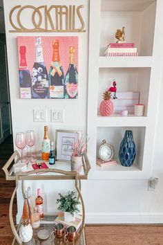 a bar cart with wine glasses and bottles on it