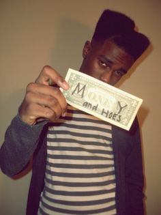 a man holding up a one dollar bill in front of his face