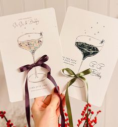 two cards with wine glasses on them are being held by someone's hand and tied together