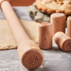 a wooden rolling pin sitting on top of a table next to some doughnuts