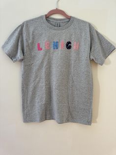 This custom embroidered patchwork t-shirt can be personalized with any word up to 10 characters long! It makes the perfect college t-shirt or a super cute way to show off your name. The opportunities are endless! Please select the fabrics that you would like for each letter by typing the numbers into the personalization box.  *If you would like a shirt with more than 10 characters or a size that is not listed, please message me or request a custom order* Please feel free to message me with any q Cotton College T-shirt With Embroidered Graphics, Cotton T-shirt With Letter Embroidery For College, Gray Cotton T-shirt With School Spirit, Trendy Crew Neck T-shirt With Letter Embroidery, Trendy Cotton T-shirt With Custom Embroidery, Cotton T-shirt With Custom Embroidery For Streetwear, College T-shirt With Letter Embroidery And Short Sleeves, Letter Embroidery Short Sleeve T-shirt For College, College Short Sleeve T-shirt With Letter Embroidery