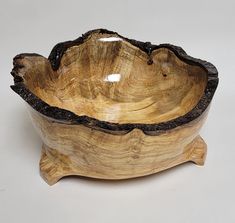 a wooden bowl sitting on top of a white table next to a black piece of wood