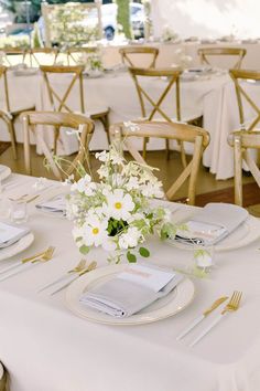 the table is set with white flowers and gold cutlery for an elegant wedding reception