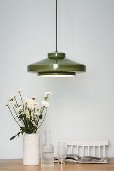 a table with vases and flowers on it in front of a light hanging from the ceiling