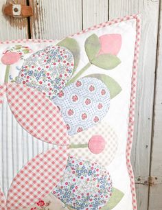 a close up of a pillow on a wooden wall with flowers and gingham