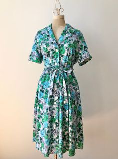 "Adorable cotton shirtdress from the 1950's with a fantastic floral print.  This vibrant number is made of super soft, medium weight cotton and features a button up front, tie belt and side hip seam pockets.  In perfect condition with no flaws to note, clean and ready to wear.  ~ Measurements ~  Bust: 42\"- 44\" snug (might cause some gaping between the buttons at 44\") Waist: 36\" Hip: open" Cotton Button-up Shirt Dress With Floral Print, Floral Print Cotton Button-up Shirt Dress, Cotton Floral Print Button-up Shirt Dress, Cotton Floral Print Short Sleeve Shirt Dress, Cotton Short Sleeve Shirt Dress With Floral Print, Cotton Floral Print Shirt Dress With Short Sleeves, Vintage Cotton Collared Shirt Dress, Vintage Cotton Shirt Dress For Daywear, Retro Button-up Floral Print Dress