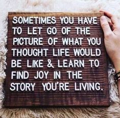 someone holding up a sign that says sometimes you have to let go of the picture of what you thought life would be like & learn to find joy in the story you're