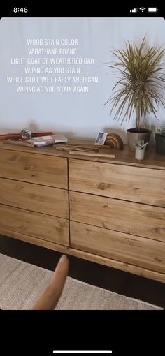 a wooden dresser sitting on top of a rug next to a plant in a pot