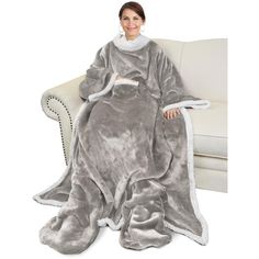 a woman is sitting on a couch wearing a gray and white blanket with sherpot