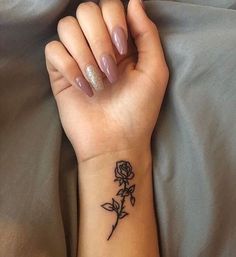 a woman's wrist with a small rose tattoo on the left side of her arm