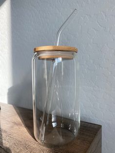 a glass jar sitting on top of a wooden table with a straw in the bottom