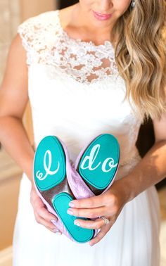 a woman in a white dress holding two pairs of shoes with the word do written on them