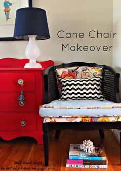 a red dresser with a black and white pillow on it next to a blue chair