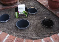 there are four pots in the ground with some plants growing out of them and a box on top