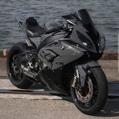 a black motorcycle parked next to the water