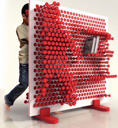 a man standing next to a red and white sculpture with circles on it's side