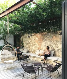 two people sitting on a patio with chairs and a hammock hanging from the ceiling