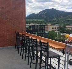 there are many chairs and tables on the balcony with mountains in the backgroud