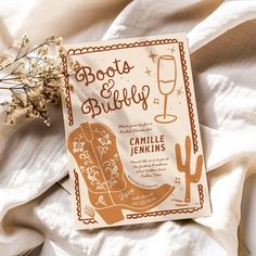 the book boots and bubbly is sitting on top of a bed with white sheets