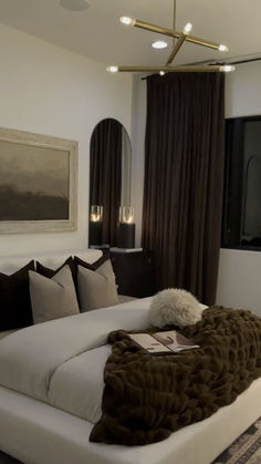 a large white bed sitting in a bedroom next to a window with brown drapes