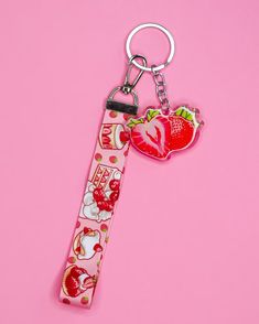 a pink keychain with strawberrys and cherries on it, sitting on a pink surface