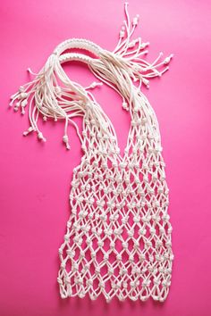 white crocheted bag on pink background