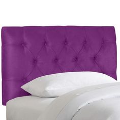 a purple headboard with white sheets and pillows