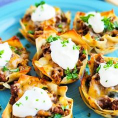 some taco shells are sitting on a blue plate with sour cream and parsley