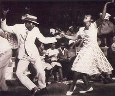 an old photo of two people dancing in front of a group of men and women